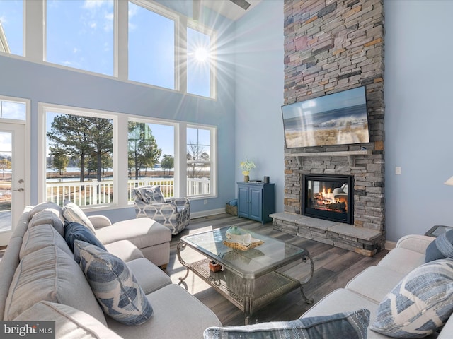 living room with a stone fireplace, baseboards, and wood finished floors