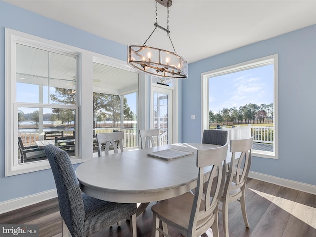 dining area featuring dark wood-style floors, a notable chandelier, and baseboards