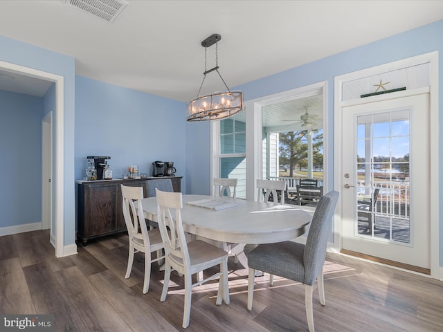 dining room with baseboards, visible vents, a notable chandelier, and dark wood finished floors