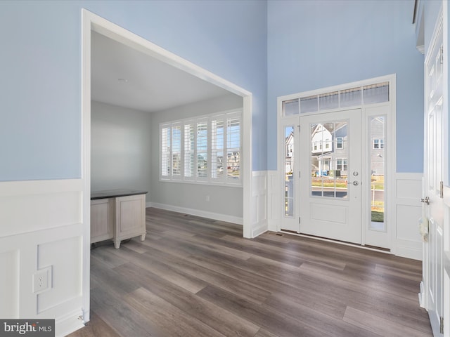 entrance foyer featuring a decorative wall, a wainscoted wall, and wood finished floors