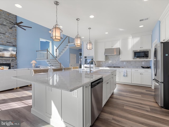 kitchen featuring visible vents, wood finished floors, appliances with stainless steel finishes, under cabinet range hood, and open floor plan