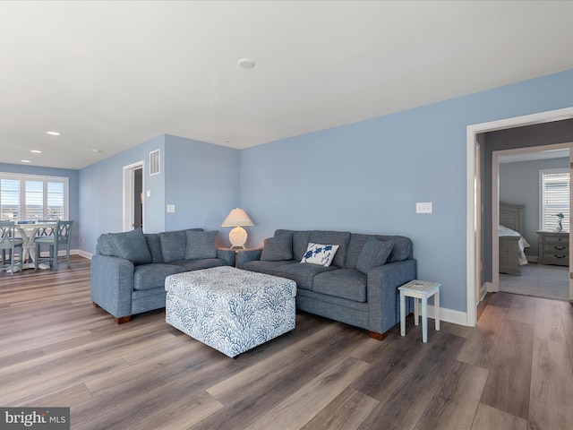 living room with plenty of natural light, baseboards, visible vents, and wood finished floors