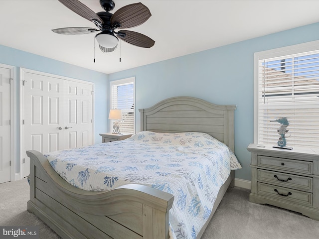 bedroom featuring a closet, ceiling fan, baseboards, and light carpet