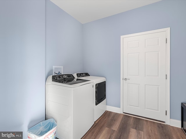 clothes washing area with dark wood finished floors, baseboards, washer and dryer, and laundry area