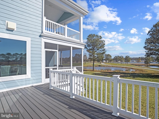 deck with a sunroom, a water view, and a yard