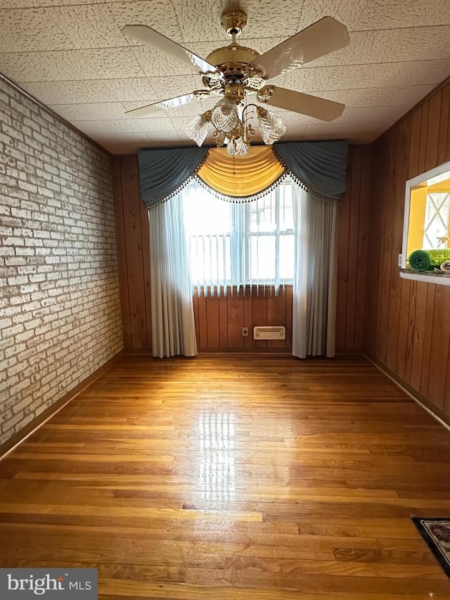 1224 Sheridan Ave, Baltimore, MD 21239 - unfurnished room with wood walls, wood finished floors, brick wall, and a ceiling fan