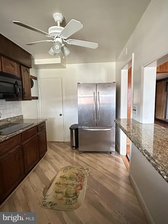 1224 Sheridan Ave, Baltimore, MD 21239 - kitchen featuring dark stone countertops, ceiling fan, black appliances, light wood-type flooring, and backsplash