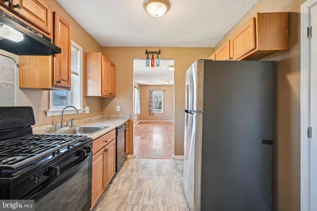 kitchen with a sink, under cabinet range hood, a wealth of natural light, and black appliances