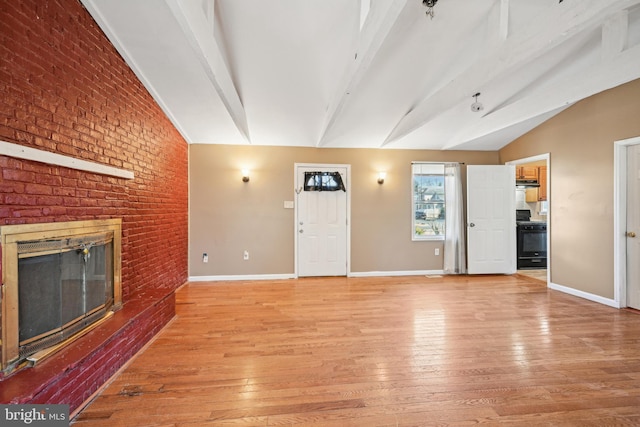 unfurnished living room with baseboards, lofted ceiling with beams, light wood-style floors, and a brick fireplace