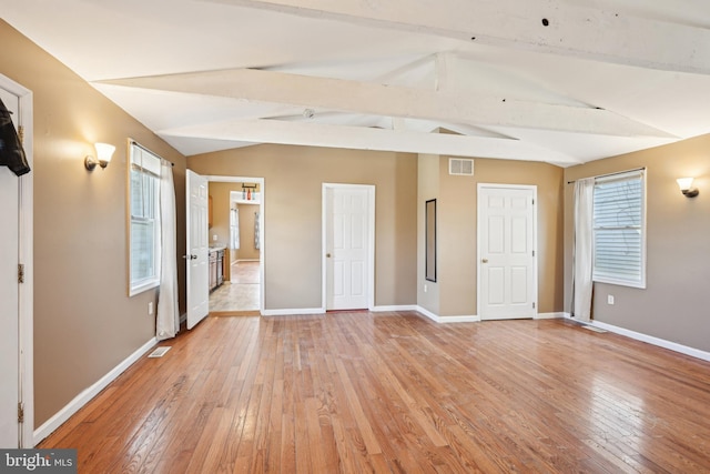 interior space featuring baseboards, visible vents, light wood-style flooring, and lofted ceiling with beams