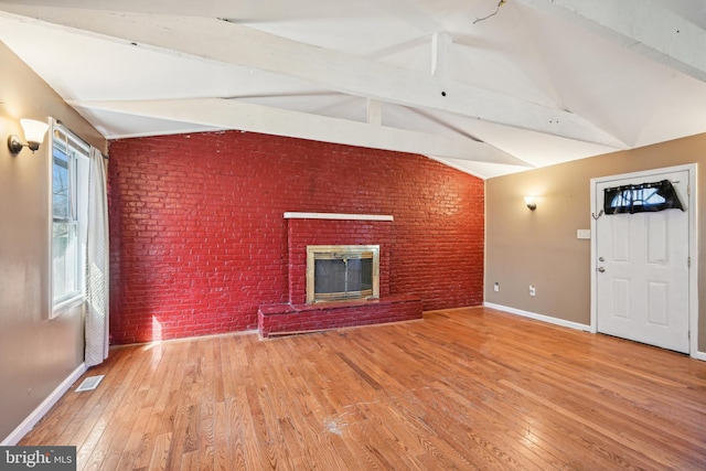 unfurnished living room featuring visible vents, lofted ceiling with beams, brick wall, and hardwood / wood-style floors