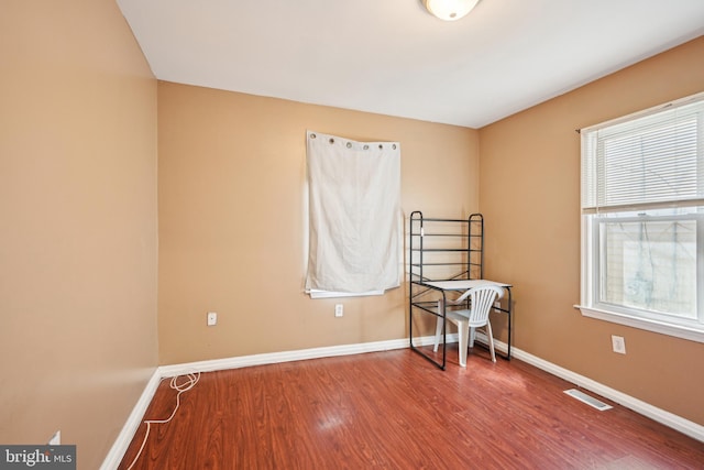 empty room with wood finished floors, baseboards, and visible vents