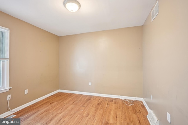 empty room with light wood-type flooring, baseboards, and visible vents