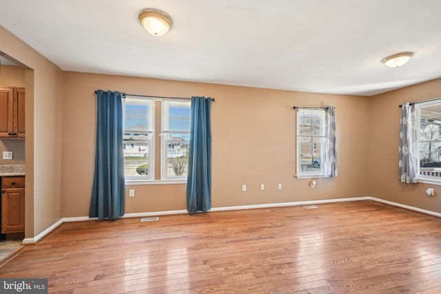 interior space featuring baseboards, light wood-type flooring, and visible vents