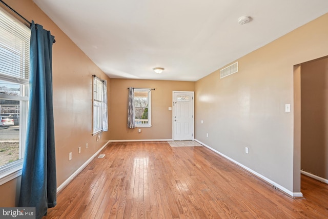 foyer with light wood finished floors, baseboards, and visible vents