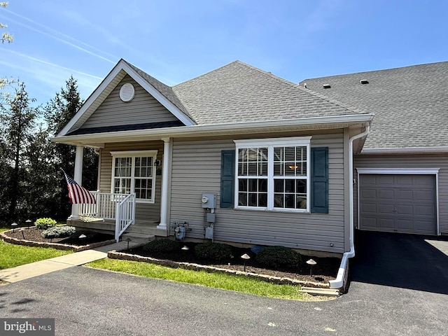 view of front of home with roof with shingles, a porch, an attached garage, and driveway