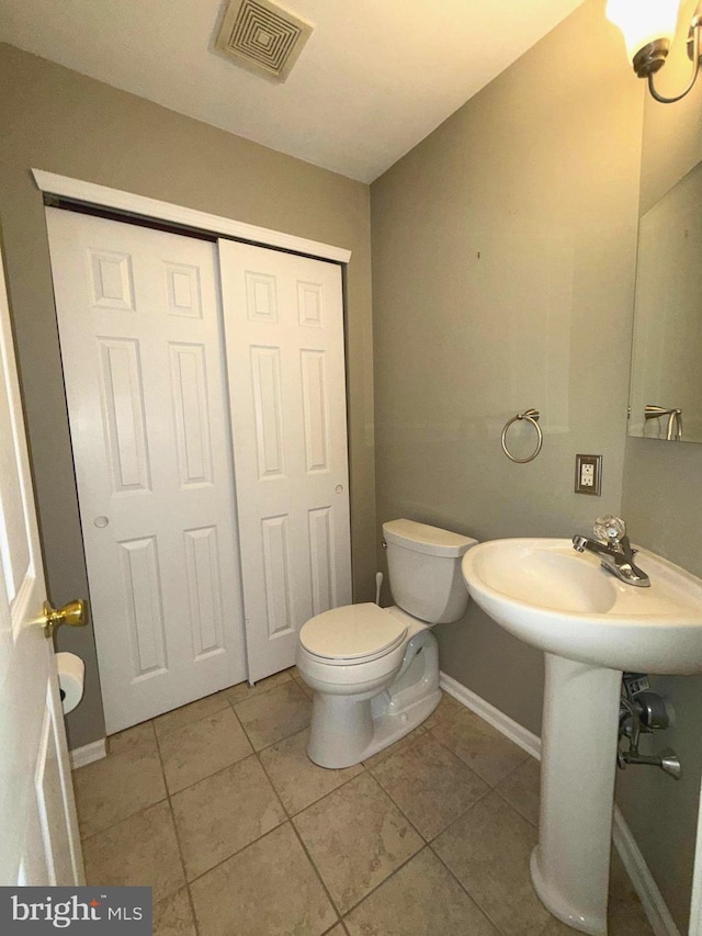 bathroom featuring visible vents, toilet, baseboards, tile patterned floors, and a sink