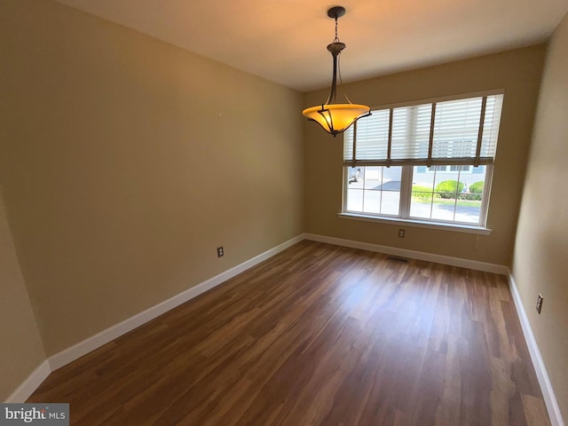 spare room featuring baseboards and dark wood-type flooring
