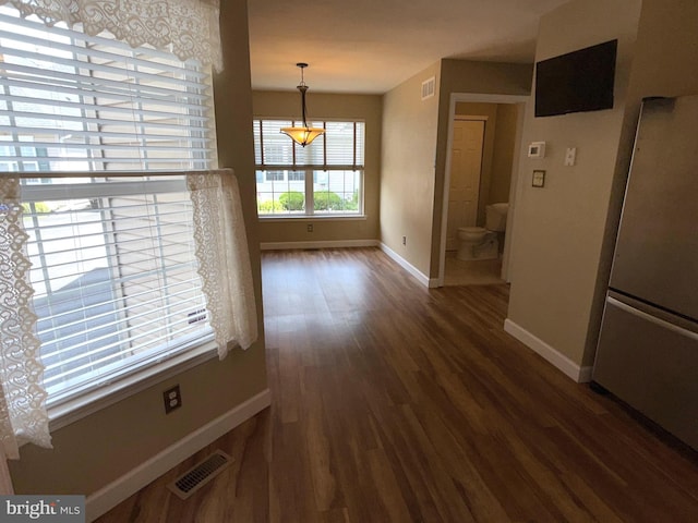unfurnished dining area with baseboards, visible vents, and wood finished floors