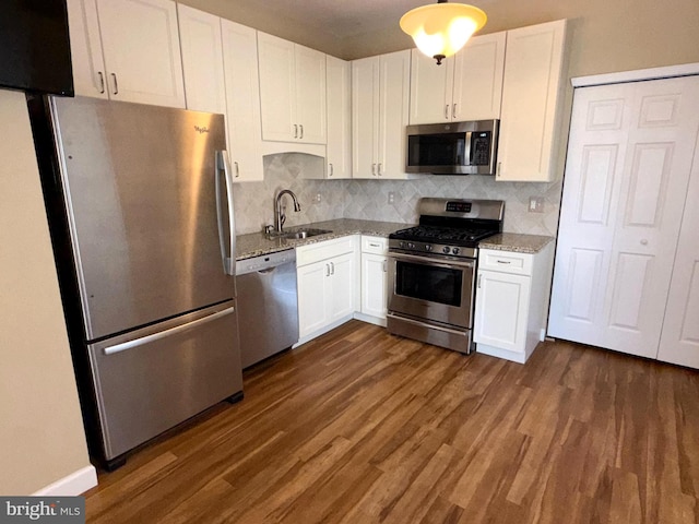 kitchen featuring dark wood-style flooring, light stone countertops, a sink, stainless steel appliances, and white cabinetry
