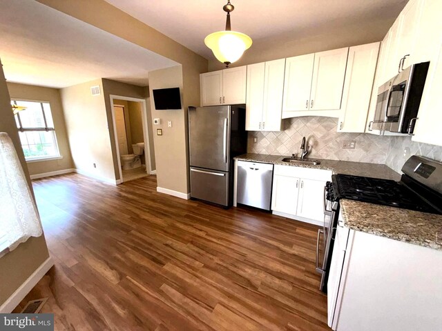 kitchen with appliances with stainless steel finishes, dark wood finished floors, white cabinetry, baseboards, and tasteful backsplash