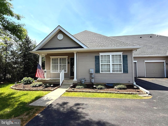 view of front of home featuring roof with shingles, a porch, an attached garage, and driveway