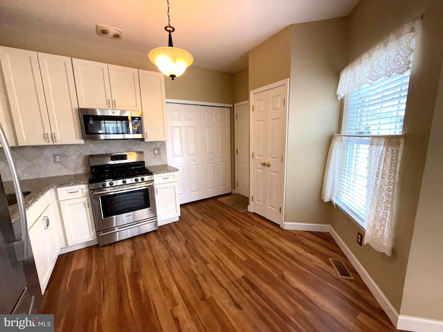 kitchen with appliances with stainless steel finishes, white cabinets, light stone counters, and visible vents