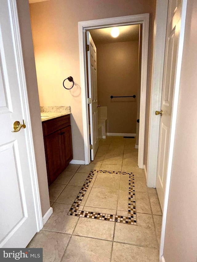 hallway featuring baseboards and light tile patterned floors