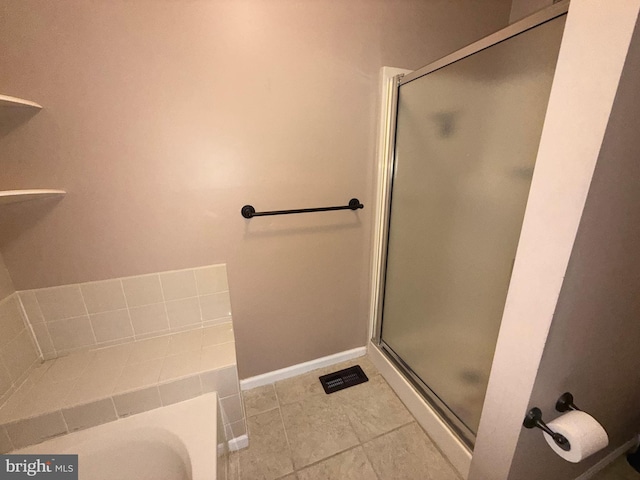 bathroom featuring tile patterned flooring, visible vents, baseboards, a bathtub, and a shower stall