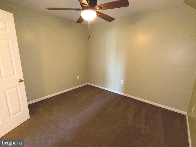 unfurnished room featuring a ceiling fan, baseboards, and dark carpet
