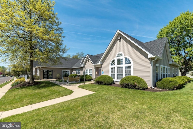 view of front of property featuring roof with shingles and a front yard