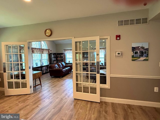 doorway with baseboards, french doors, wood finished floors, and visible vents