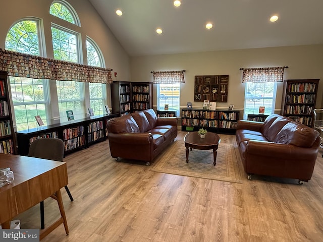 living area featuring a healthy amount of sunlight, high vaulted ceiling, wall of books, and recessed lighting