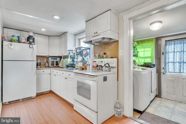 kitchen with light countertops, white cabinets, white appliances, under cabinet range hood, and washer and dryer