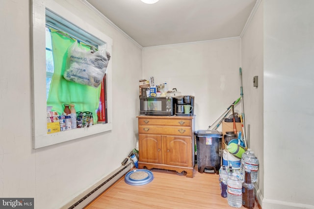interior space featuring ornamental molding, wood finished floors, and baseboard heating