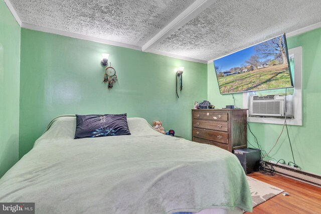bedroom featuring a textured ceiling, wood finished floors, crown molding, and a baseboard radiator