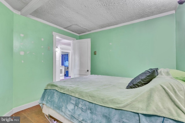 bedroom featuring baseboards, a textured ceiling, ornamental molding, and wood finished floors