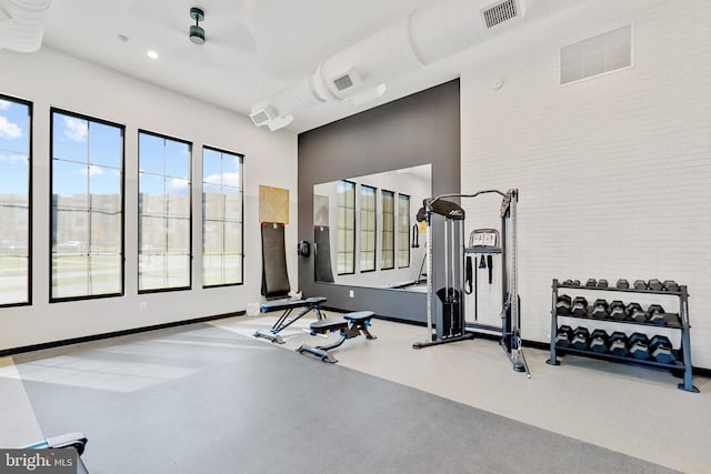 exercise room featuring baseboards, recessed lighting, and brick wall