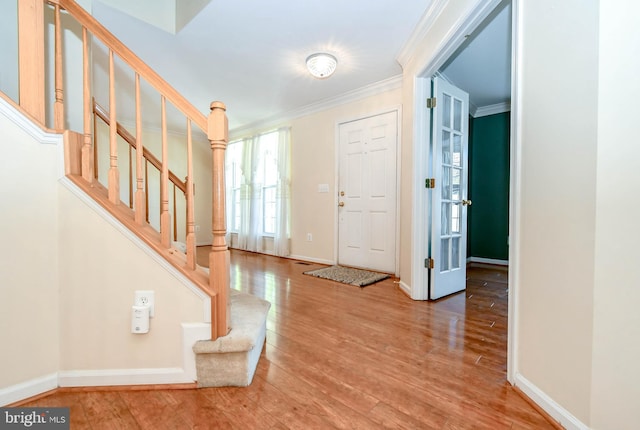 foyer entrance featuring stairs, crown molding, wood finished floors, and baseboards
