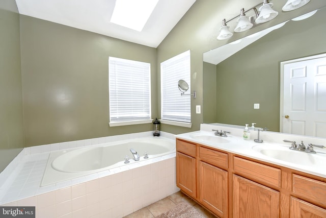 bathroom featuring vaulted ceiling with skylight, a garden tub, tile patterned floors, and a sink