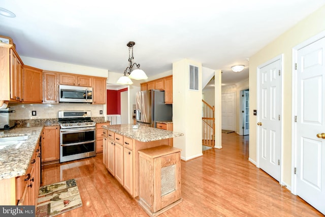 kitchen with stainless steel appliances, visible vents, light wood-type flooring, a center island, and decorative backsplash