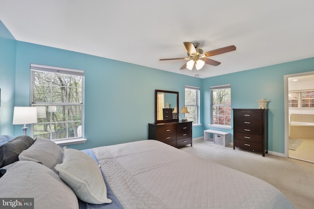 bedroom with ensuite bath, a ceiling fan, baseboards, and light colored carpet