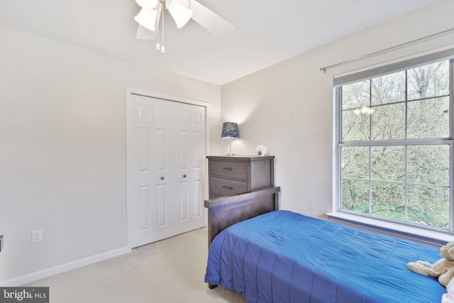 bedroom with baseboards, light carpet, a ceiling fan, and a closet