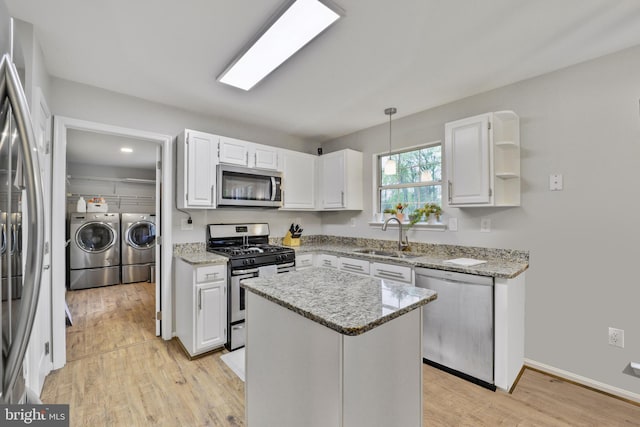 kitchen featuring washer and dryer, appliances with stainless steel finishes, a sink, and white cabinets