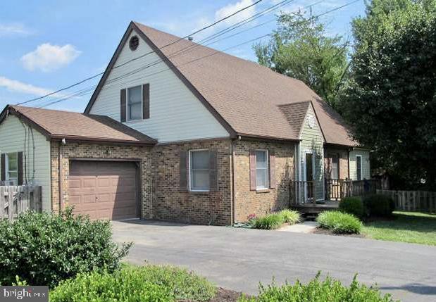 view of front facade with an attached garage, fence, brick siding, and concrete driveway