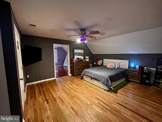 bedroom with lofted ceiling, visible vents, a ceiling fan, and hardwood / wood-style flooring