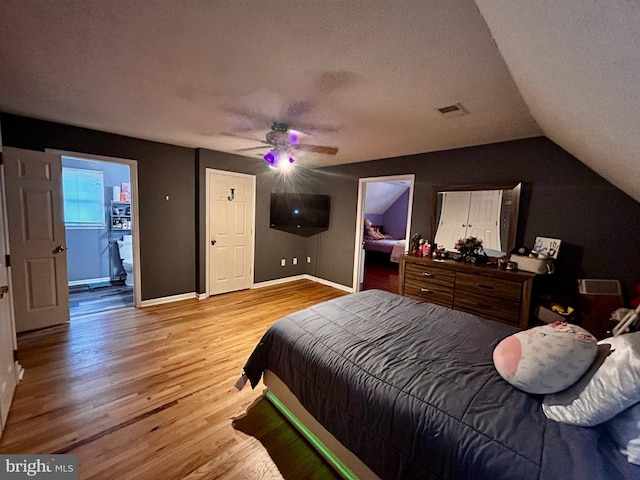bedroom with a textured ceiling, lofted ceiling, visible vents, and light wood finished floors