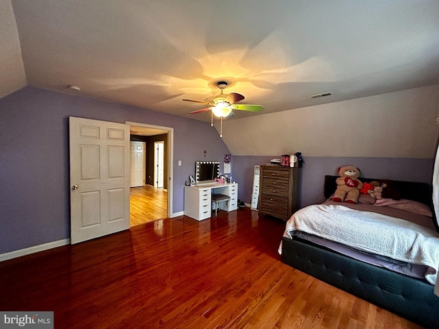 bedroom with vaulted ceiling, wood finished floors, visible vents, and baseboards