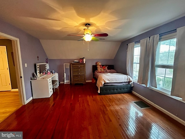 bedroom with baseboards, wood finished floors, visible vents, and vaulted ceiling