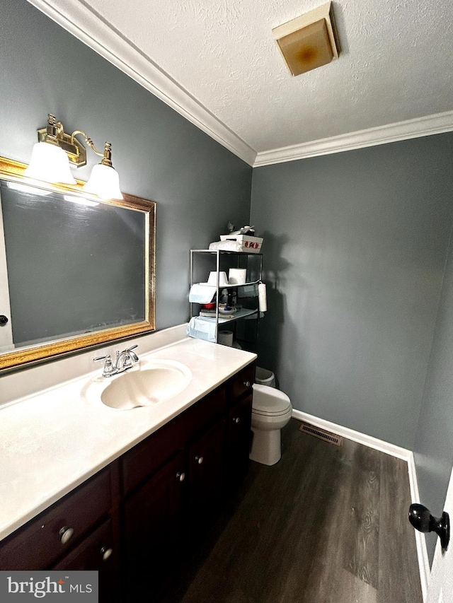 half bath featuring wood finished floors, crown molding, vanity, and toilet